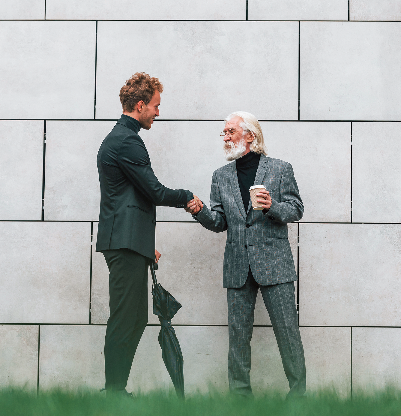 2_people_shaking_hands_formal_white_wall_outside
